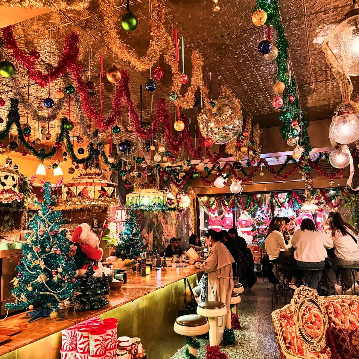 Bar de la Taverne de Noël à Montréal décoré de guirlandes, de boules et de sapins de Noël
