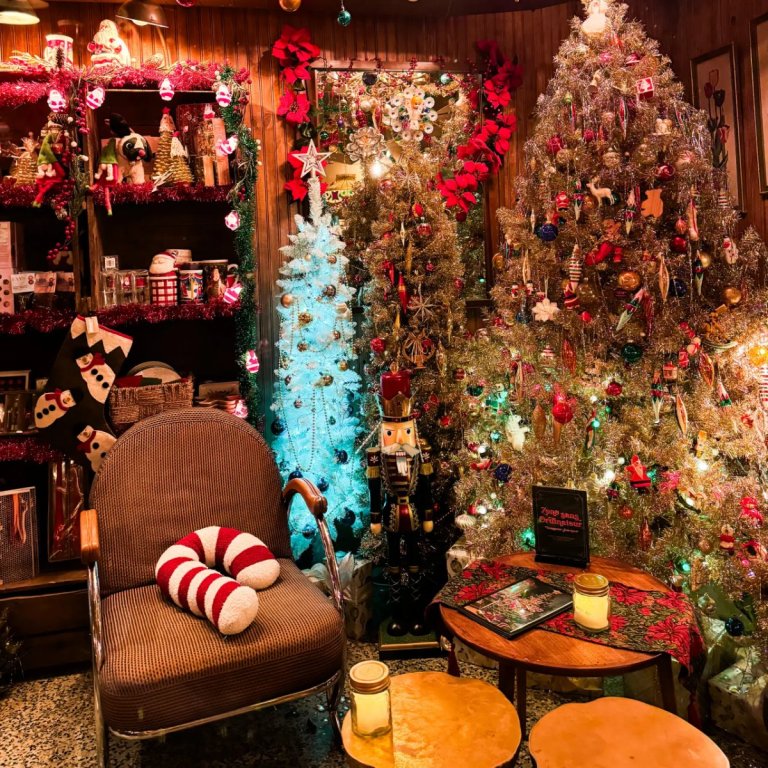 Coin salon avec fauteuil, coussin sucre d'orge et sapins décorés à la Taverne de Noël du Petit Dep